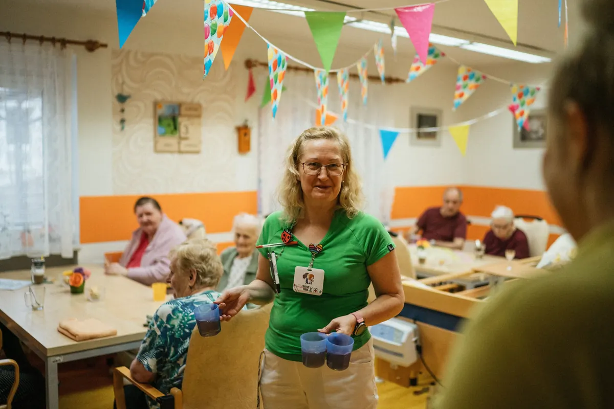 Caregiver serving drinks to residents in an assisted living dining room